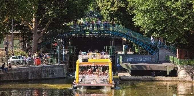 Imagem de pessoas passeando dentro de barco no Canal St. Martin em Paris