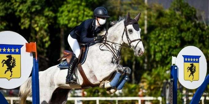 Atleta de jóquei montado em cavalo dando salto