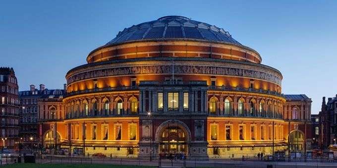 Imagem da frente do Royal Albert Hall ao anoitecer, em Londres. 