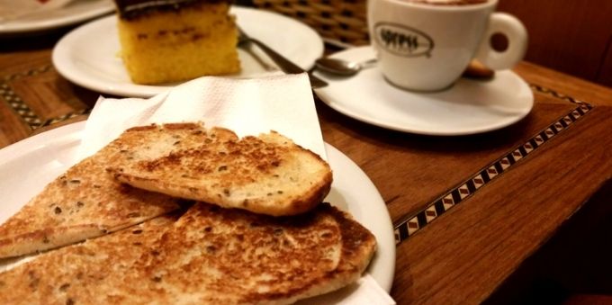 Imagem fechada mostra pão na chapa e xícara de café no Leblon. 