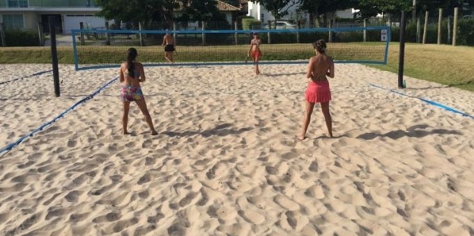Imagem mostra mulheres jogando vôlei de praia em Jurerê