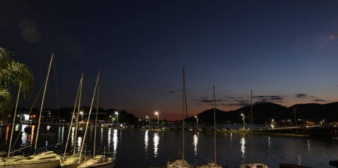 Imagem noturna mostra barcos na Lagoa de Conceição. 