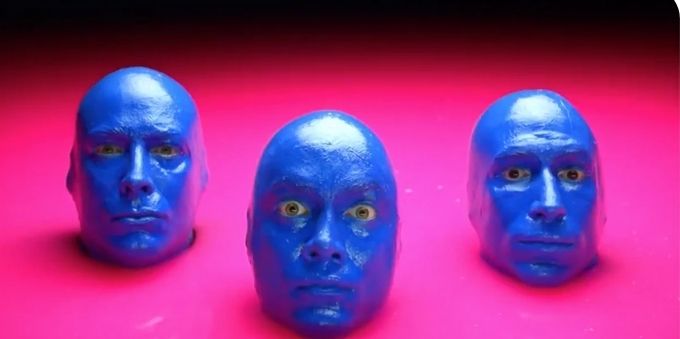 Imagem do rosto de três homens pintados de azul - blue man, em Orlando. 
