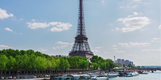 Paris: imagem de Torre Eiffel ao fundo e rio passando na frente, com barcos estacionados
