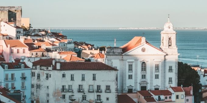 Imagem mostra prédios e igreja tradicionais no bairro Alfama, na pequena Lisboa 