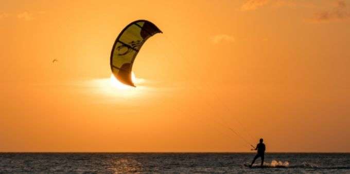 Imagem mostra prática do esporte Kitesurf no entardecer de Jurerê