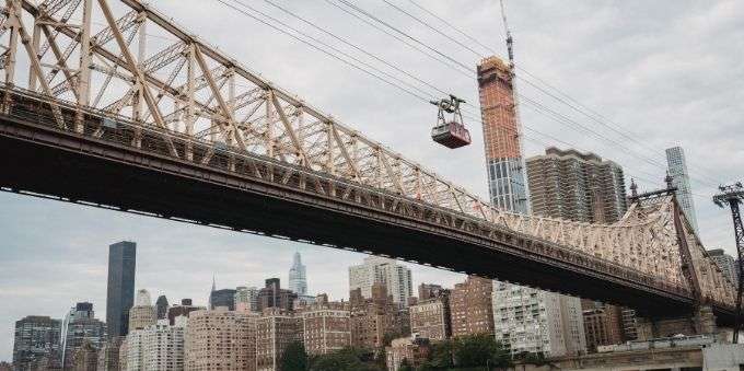 Nova York: imagem aberta de bondinho atravessando cidade ao lado de ponte