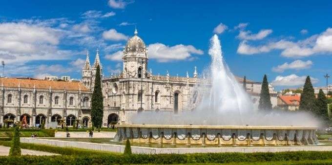 Imagem aberta mostra fachada do mosteiro Jerónimos, em Lisboa, com fonte de água na frente 