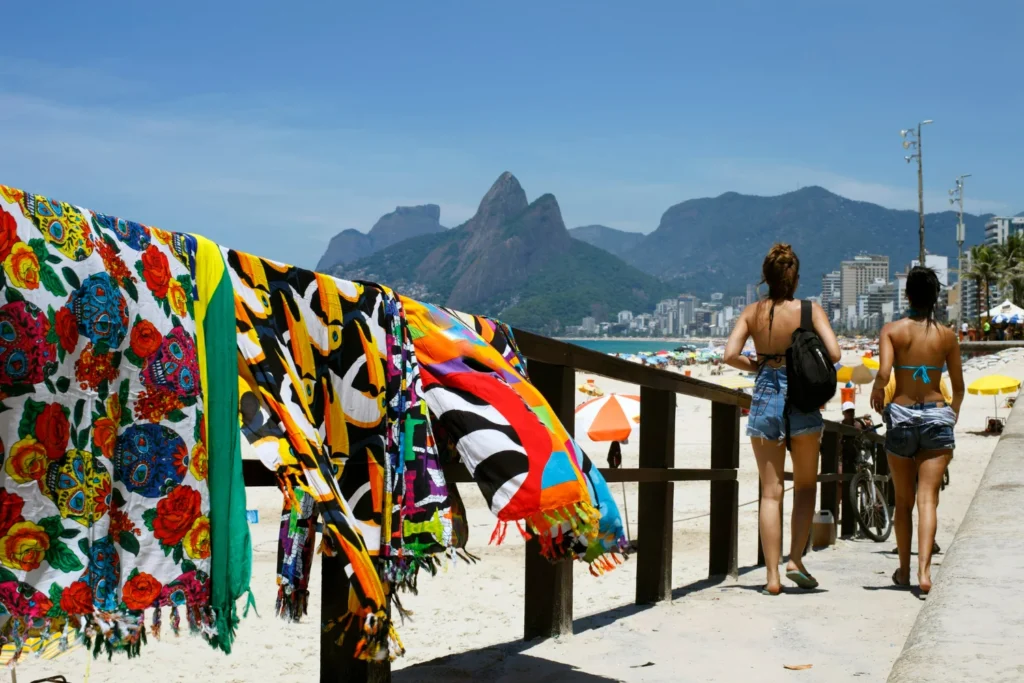 duas mulheres caminhando no calçadão da Praia de Ipanema, enquanto voam saídas de praia em um muro